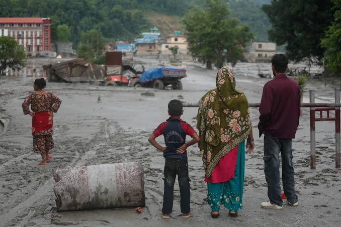 A family looking across a flood-affected community in Nepal